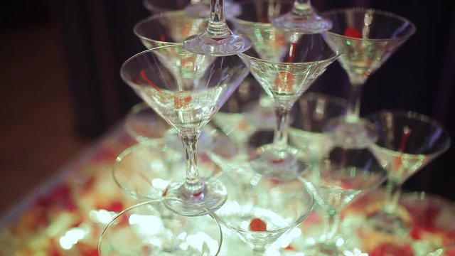 Champagne pyramid for parties with cherries. Glasses with champagne and dry ice in the form of a slide. Smoke of Champagne. Close-up.