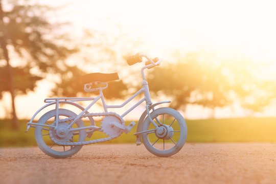 Blue vintage bicycle toy waiting outdoors at sunset light.