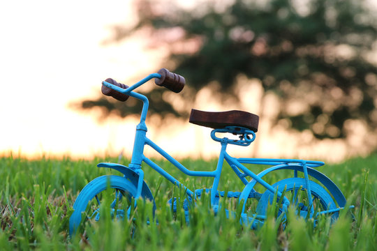 Blue vintage bicycle toy waiting outdoors at sunset light.