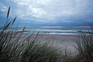 view of the beach and the sea at dusk against the background of a long grass, long exposure