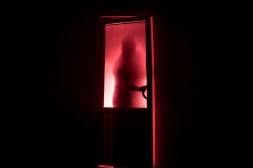 Silhouette of an unknown shadow figure on a door through a closed glass door. The silhouette of a human in front of a window at night. Scary scene halloween concept