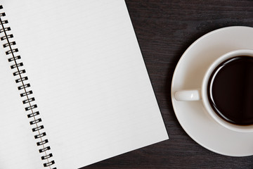 Top view of coffee cup and blank notebook for memo on wooden background. Business and object concept. Memo and reminder theme.