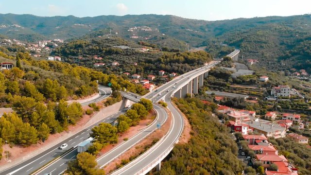 Aerial slow motion: flying near multiple lane highway crossing villages and forest hills (Autostrada dei Fiori - A10) Liguria Italy 