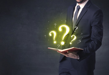 Businessman holding a book with question mark symbol.