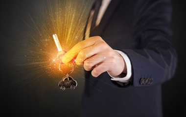 Formal man hand over shiny keys with dark background
