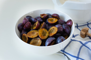 Ingredients for a Plum Cake, Plums, Flour, with a Whisk on a white Table, High Key