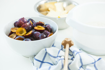 Ingredients for a Plum Cake, Plums, Flour, Butter, with a Whisk on a white Table, High Key