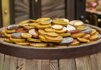 A lot of gold coins on a wooden barrel, the concept of wealth