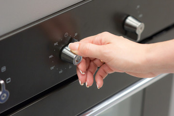The girl sets the temperature in the oven