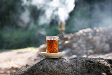 Eastern black tea in glass on a eastern carpet. Eastern tea concept. Armudu traditional cup. Sunset background. Selective focus
