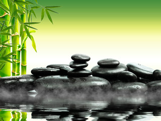 Zen basalt stones with green bamboo on water. Spa and Wellness concept.