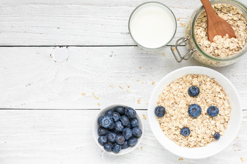 homemade oat muesli with fresh blueberries and milk on white wooden background. healthy breakfast. top view