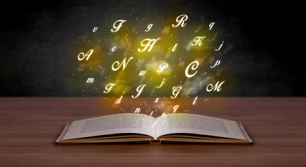 Glowing yellow alphabet letters coming out of an open book 