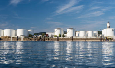 Storage silos,fuel depot of petroleum and gasoline on the banks of the river in western Germany on a beautiful blue sky with clouds.
