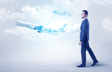 Elegant businessman going somewhere with briefcase and airplane on the background
