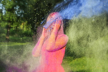 Emotional blonde girl with exploding colorful paint celebrating Holi festival