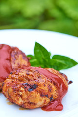Grilled chicken Legs with tomato sauce and herbs on a plate.