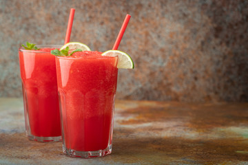 Watermelon slushie with lime, summer refreshing drink in tall glasses on a blue rusty background. with copy space