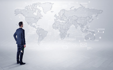 Fototapeta premium Businessman standing with his back and looking at a worldwide map with objects in his hand 