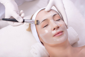 Portrait of beautiful woman getting beauty skin mask treatment on her face with brush