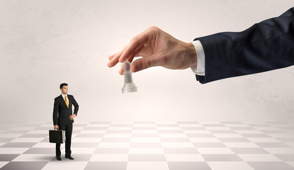 Fototapeta premium Small businessman fighting against big chessman on a big hand with chess board concept 