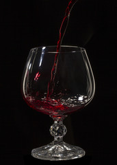 Naklejka na ściany i meble Glass still life image A glass of red wine in a glass on a black background