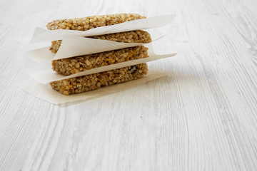 Granola bars on baking sheet over white wooden background, side view. Close-up.