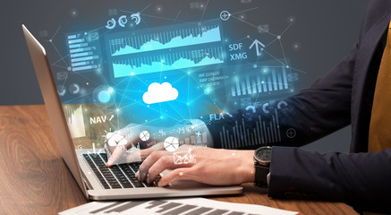 Businessman hand typing on laptop with reports and graphs concept around
