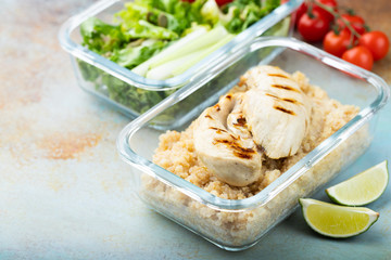 Healthy meal prep containers with quinoa, chicken breast and green salad overhead shot with copy space
