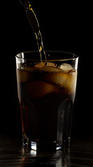 Glass still life image Cola with ice in a glass on a black background
