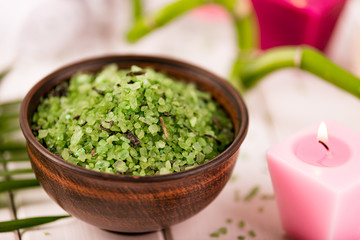 Spa. Green herbal spirulina salt in ceramic bowl, spa towels, pink scented candle and bamboo