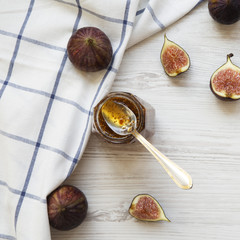 Glass jar of fig jam and fresh figs on white wooden background, view from above. Top view, overhead.