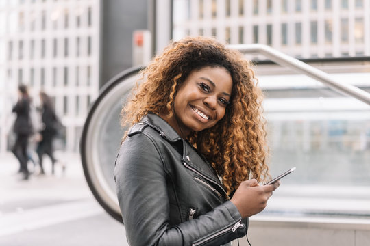 Young smiling black woman holding mobile phone