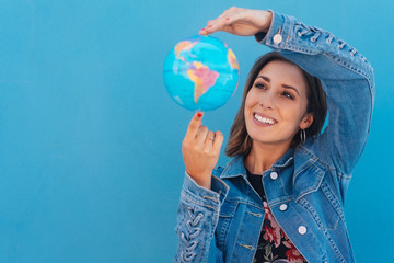 Happy young woman spinning a globe in her hands