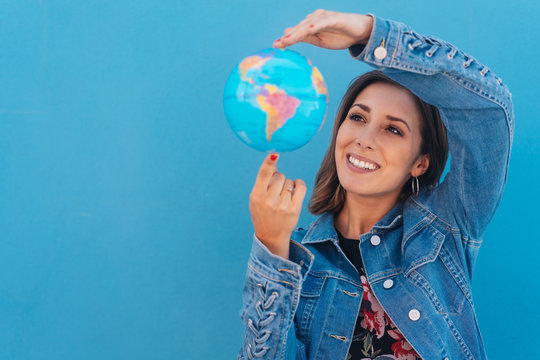 Happy Young Woman Spinning A Globe In Her Hands