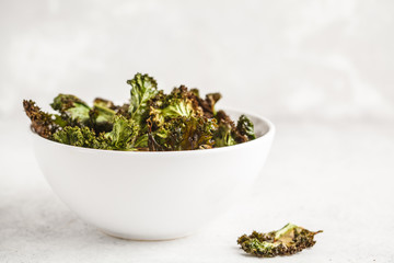 Fototapeta na wymiar Kale chips in a white bowl on white background. Clean eating concept.