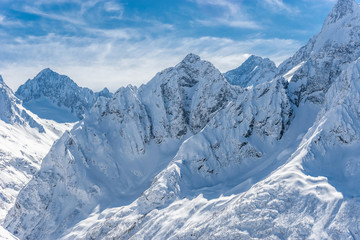Snow covered winter Caucasian mountains in sunny day. Dombai ski resort, Karachai-Cherkess, Russia.