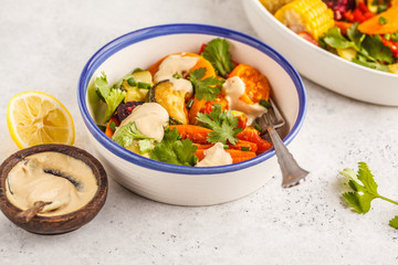 Salad with baked vegetables with tahini in white plate, white background. Clean eating concept.