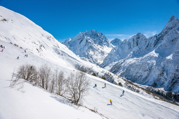 Fototapeta na wymiar Ski slope with Mt. Dombay-Ulgen on the horizon in winter sunny day. Dombai ski resort, Western Caucasus, Russia.