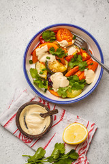 Salad with baked vegetables with tahini in white plate, white background, top view. Clean eating concept.