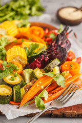 Baked vegetables: pumpkin, beets, carrots, peppers, zucchini and corn on wooden board.