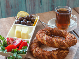 turkish bagel on wooden table, tea and breakfast plate. Tomatoes, cheese, olives