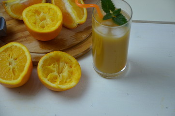 glass of fresh orange juice with fresh fruits on white table.