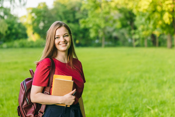 Happy student girl with notes and backpack. Entering the university, starting school in September