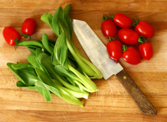 Fresh baby pak choi and tomatoes on wooden chopping board 2