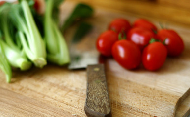 Fresh baby pak choi and tomatoes on wooden chopping board 1