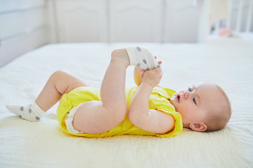 Adorable baby girl removing sock from her foot