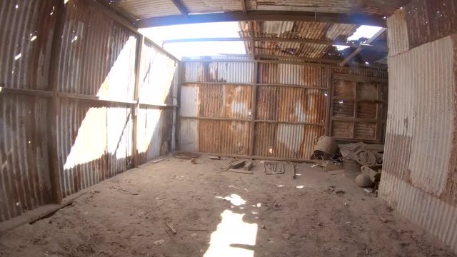 Abandoned Humberstone and Santa Laura saltpeter works factory, near Iquique, northern Chile, South America. Walking inside industry warehouse building rusty and light leaking from holes.