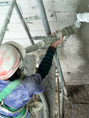 Construction workers plastering wall using cement plaster at the construction site. They are...