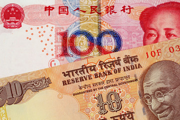 A close up image of a 100 Chinese yuan bank note with a 10 Indian Rupee bank note 